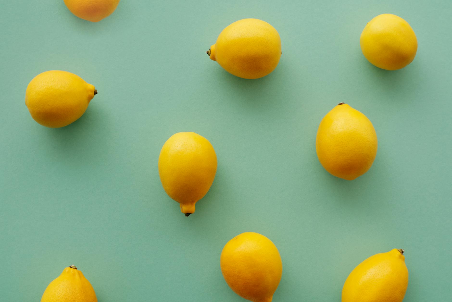 Bright yellow lemons arranged on a pastel green background, symbolizing the refreshing approach to synchronized pleasure timing