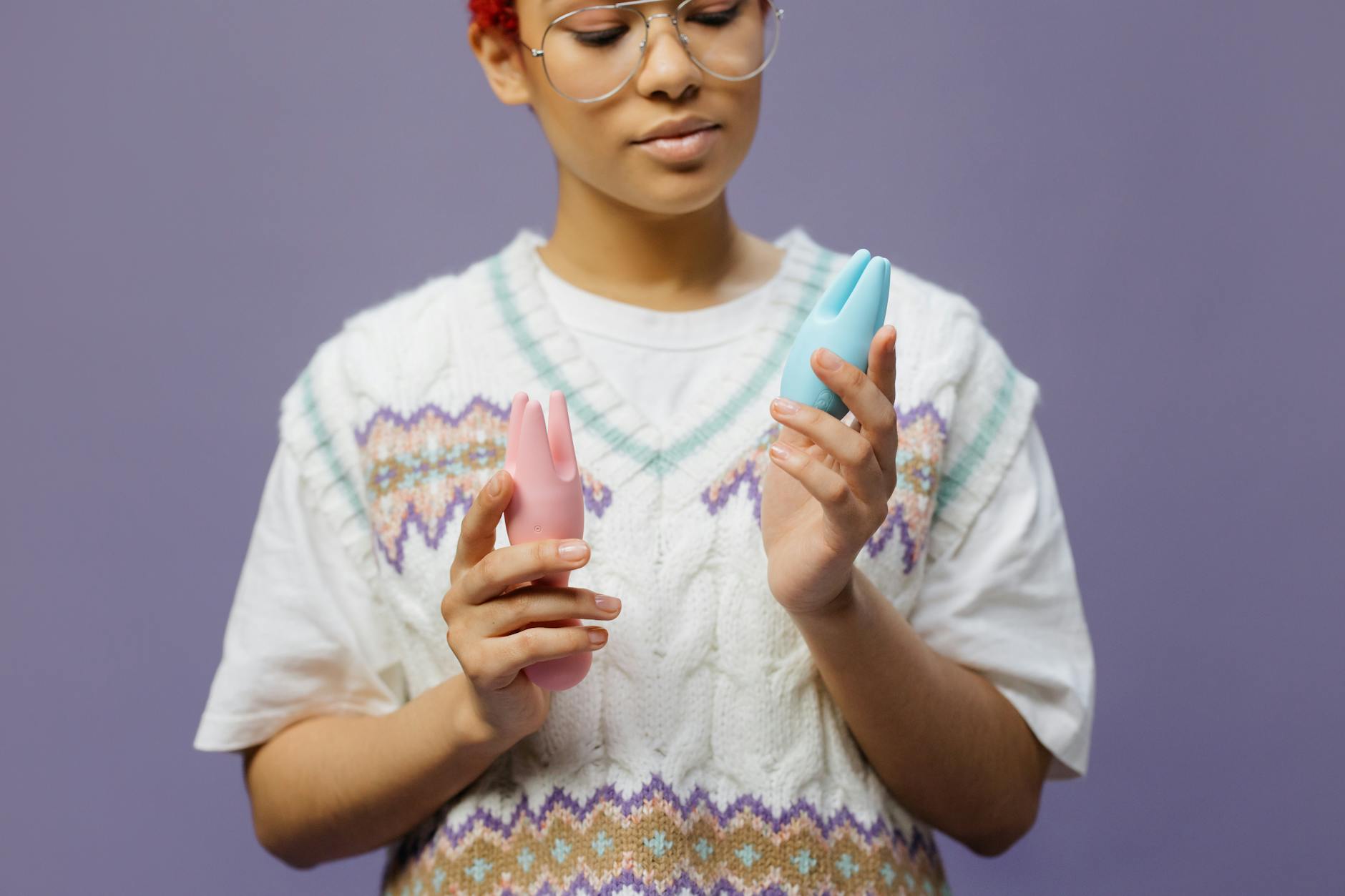 Woman contemplatively holding colorful vibrators, reflecting on rebuilding intimate connection