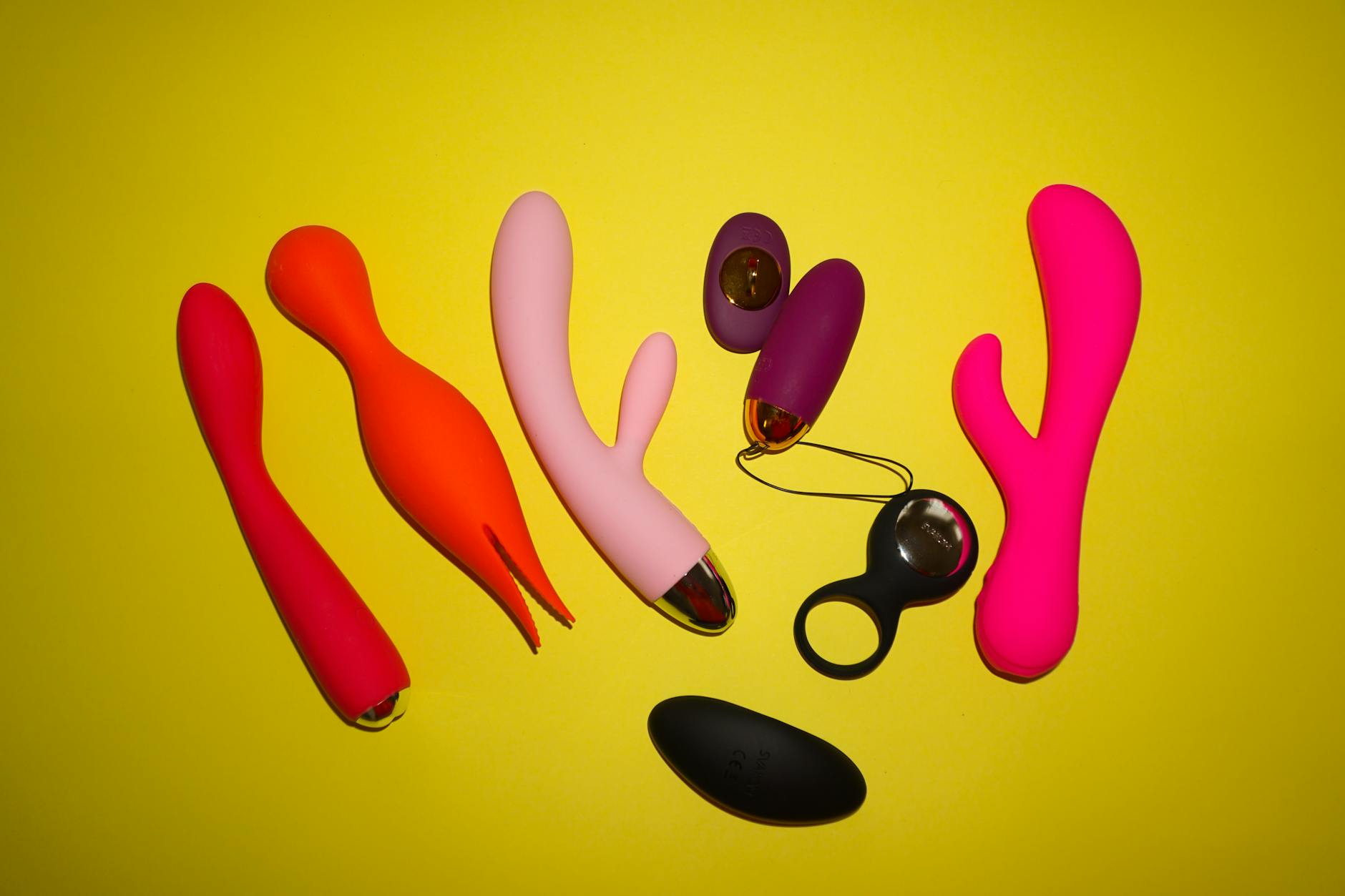 A blue silicone clitoral vibrator held in hand against a purple background