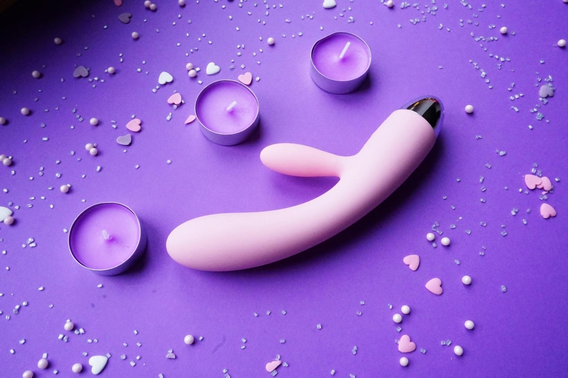 Hand holding a lemon on a soft pink background, symbolizing the gentle lemon vibrator design